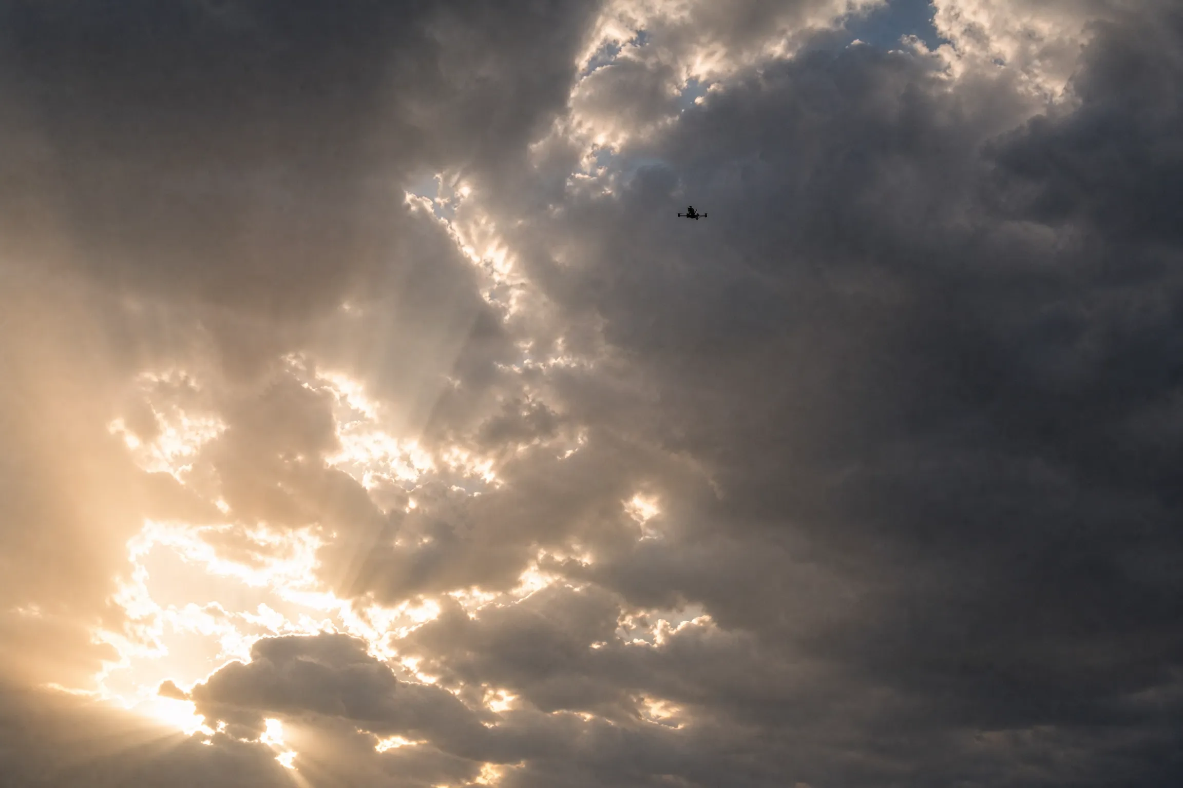 An Unmanned Industries airframe climbing into backlit cloud